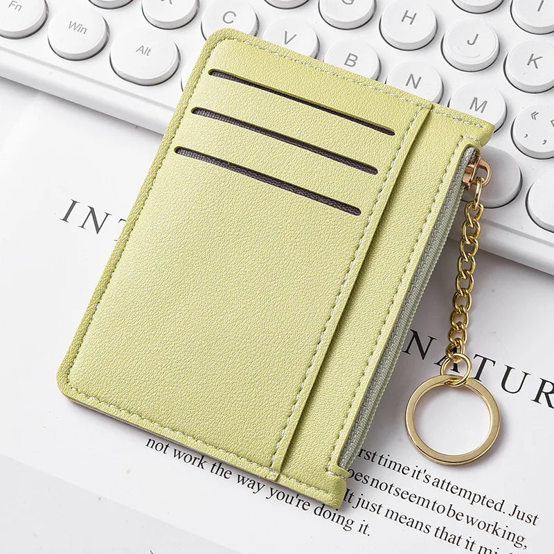 Dünne hellgrüne Kartenwallet mit Reißverschluss auf einer weißen Tastatur.