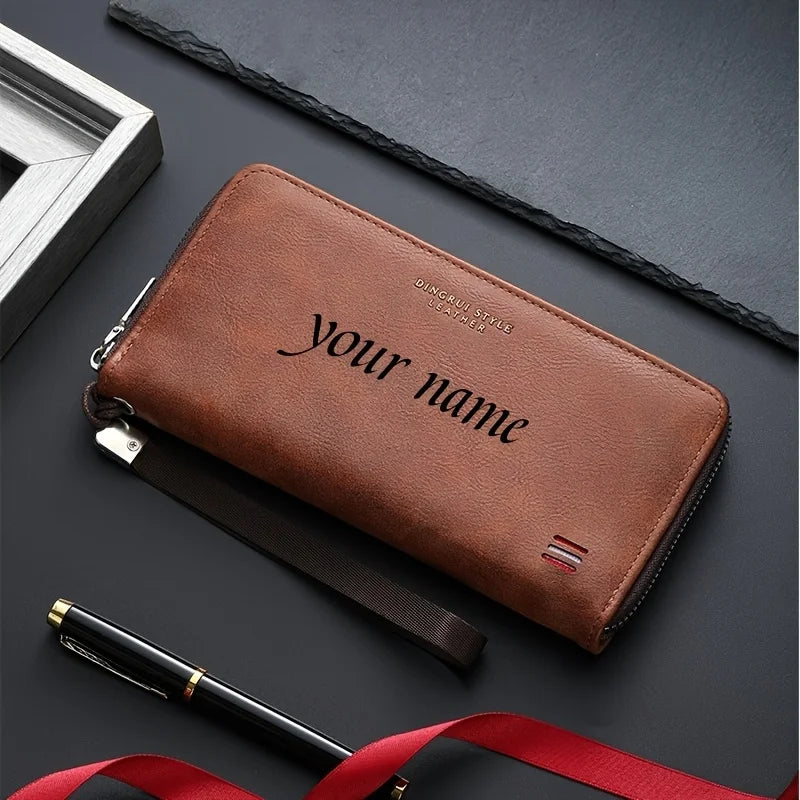 A brown leather wallet with the text Your name embossed on it, lying next to a pen and a red ribbon.