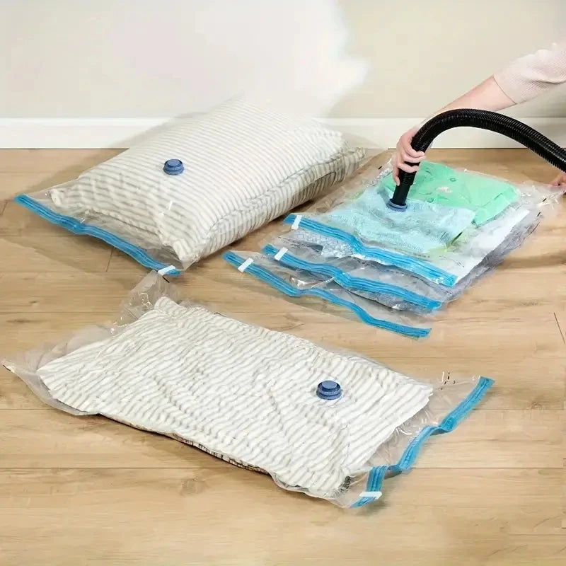 Three reusable vacuum compression storage bags of varying sizes and colors are shown on a wooden floor.