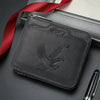 A dark gray embossed PU leather slim wallet with a silver zipper and a red ribbon lying next to it.
