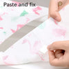 Hands are shown applying or fitting a pink patterned disposable toilet seat cover onto a white surface.