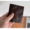 A hand holds a dark brown genuine leather bifold wallet for men.