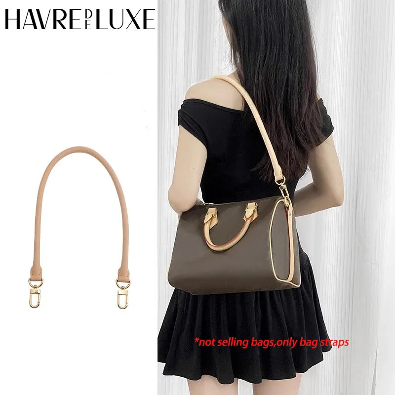 A woman is holding a brown leather bag with gold hardware and a matching strap against a white background.