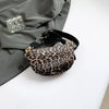 Leopardenmuster-Crossbody-Bauchtasche mit schwarzem Riemen auf einem grauen Blazer.