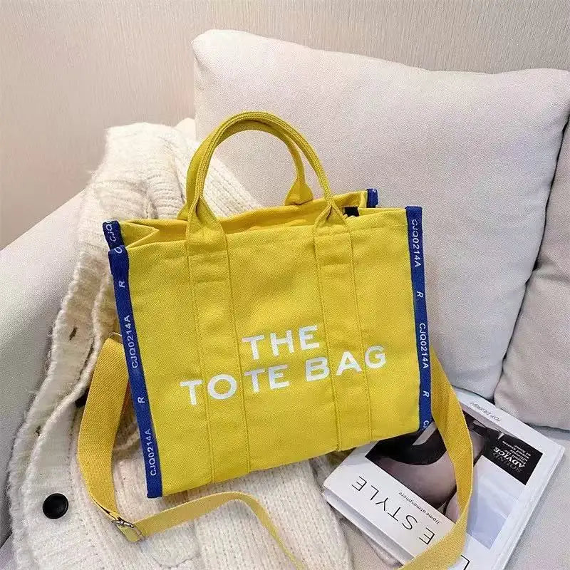 A bright yellow tote bag with blue trim is displayed against a white background.