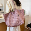 A light pink leopard print canvas tote bag is shown hanging on a person's shoulder against a white background.