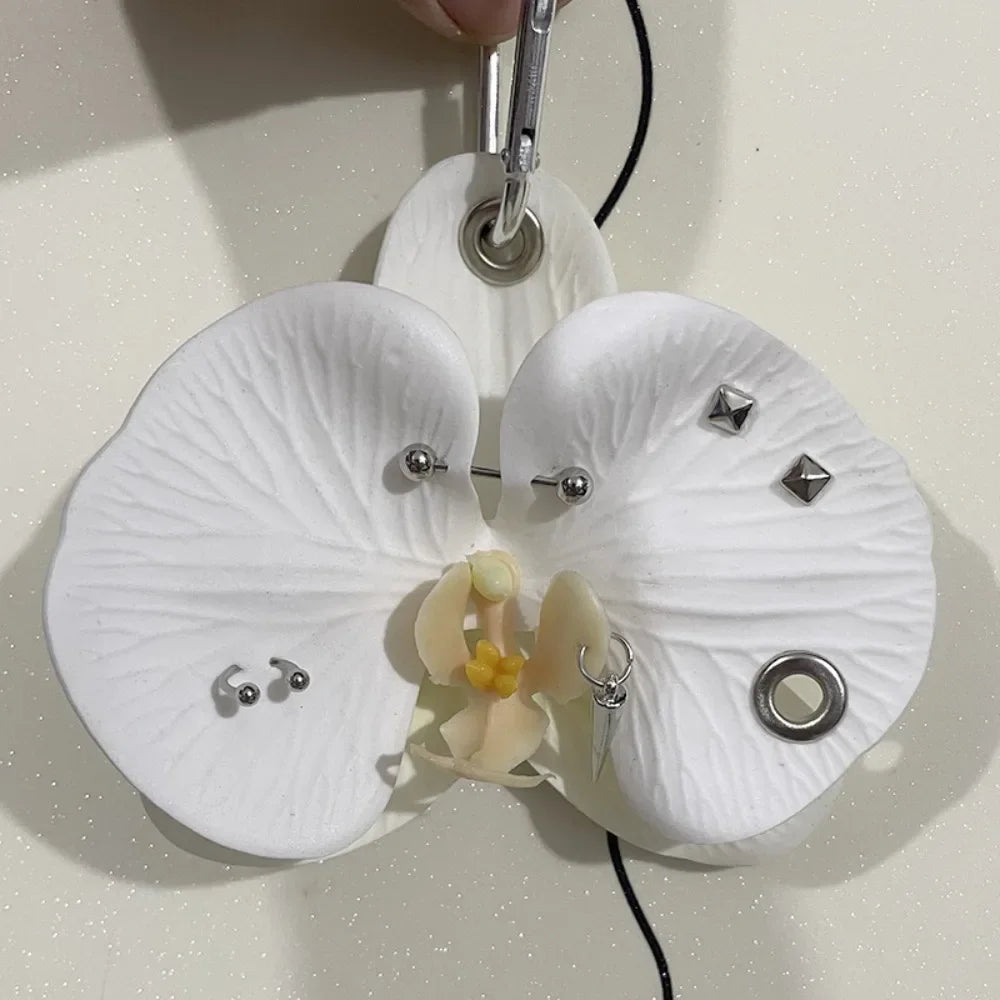 A white realistic phalaenopsis orchid flower shaped keychain with a silver charm.