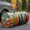 A quilted travel duffle bag featuring a colorful, nature-inspired floral pattern resting on asphalt.