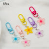 Five colorful resin flower keychains in pink, yellow, purple, and blue on silver chains
