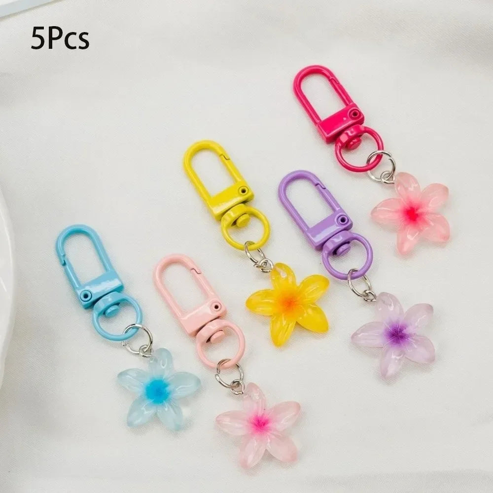Five colorful resin flower keychains in pink, yellow, purple, and blue on silver chains