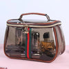 A luxury transparent cosmetic bag with a brown leather trim and a dark glass body containing various bottles.