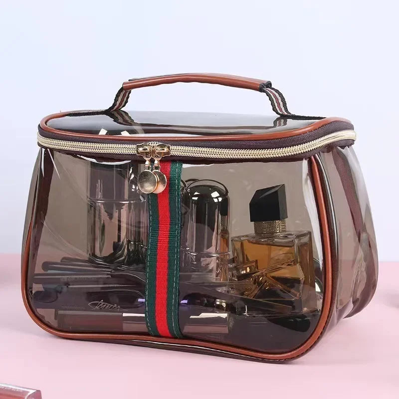 A luxury transparent cosmetic bag with a brown leather trim and a dark glass body containing various bottles.