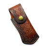 A brown leather knife sheath with a decorative pattern and a round olive green button.