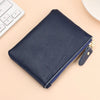 A dark navy genuine leather mini zipper coin and card purse resting on a light beige surface next to a white computer keyboar