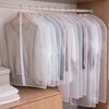 Clear garment dust covers for hangers displayed on a wooden rack.