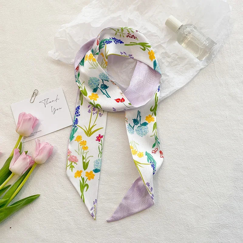 Foulard floral en soie noué en nœud, fond blanc avec motifs floraux colorés.