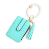 A turquoise leather card holder with a gold keychain and a light pink beaded bangle.