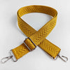 A mustard yellow woven strap with an arrow jacquard pattern, folded in an X shape.