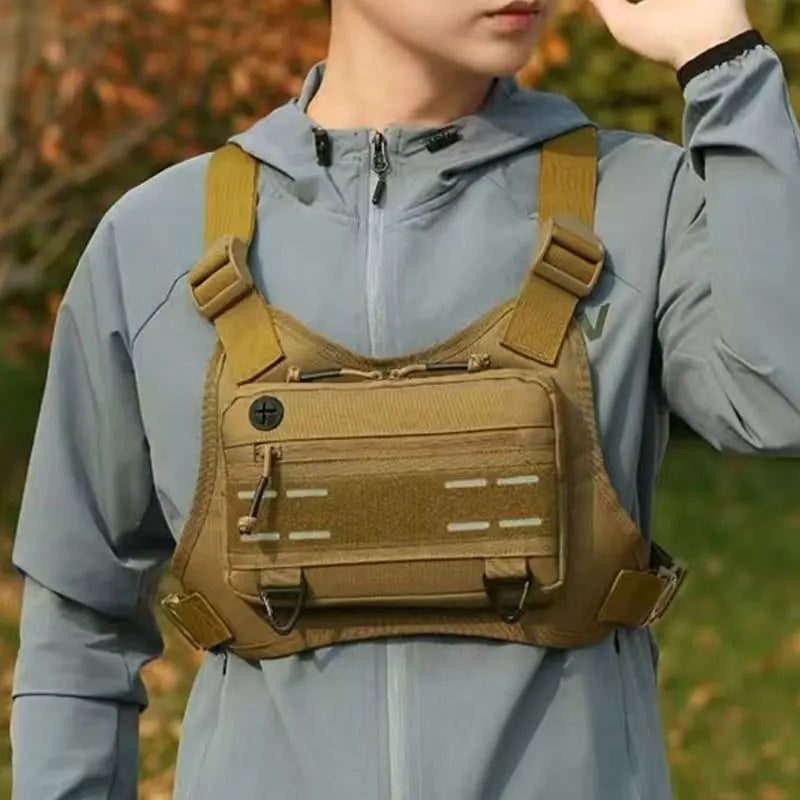 A close-up of a male wearing a tan tactical chest rig vest bag over a light blue hoodie.