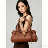 A woman holds a brown vegan leather tote bag with a gold lock buckle clip.