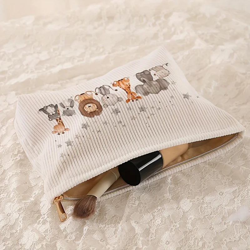 A light beige corduroy makeup storage pouch with a pattern of various animal heads and stars, lying on a white lace surface.