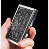 A hand holds a silver metal cigarette case holder featuring intricate black engraving.