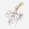 A white and black striped fabric bow bag chain strap extension with a gold-toned ring.