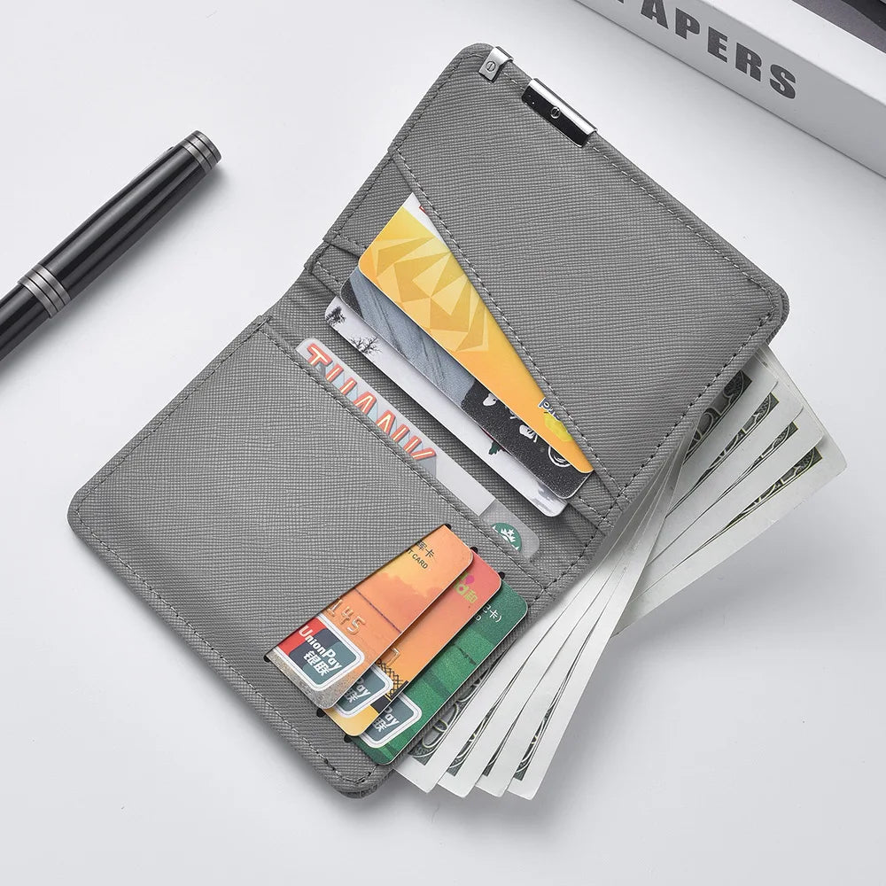 A gray slim faux leather business card wallet holding several cards and a pen.