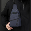 A navy blue lightweight nylon crossbody sling bag is shown attached to a black jacket.