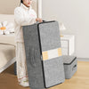 A woman stands next to a gray foldable underbed storage bag in a bedroom setting.