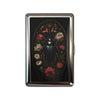 A vintage snap metal card holder with a dark background featuring an ornate floral design.