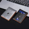 A black and silver slim genuine leather RFID blocking wallet with blue accents placed on a laptop keyboard.