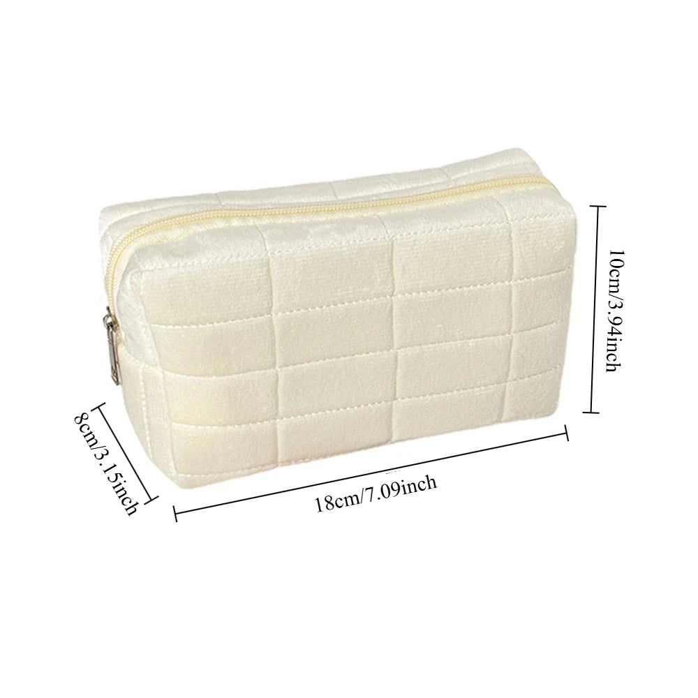 A cream-colored quilted velvet cosmetic and toiletry bag shown from the top view.
