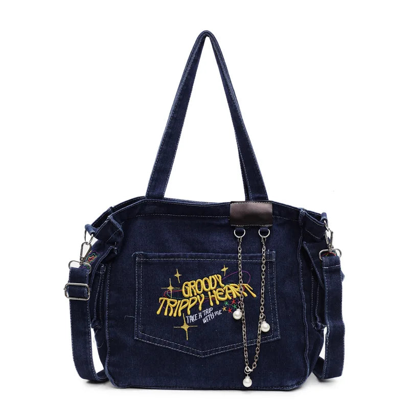 A dark blue denim crossbody bag with a flap and chain detail is shown against a white background.