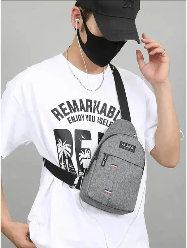 A man wearing a black mask and a white t-shirt holds a gray waterproof crossbody fanny pack.