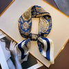 A blue and gold paisley silk hair scarf tied in a bow, displayed on a framed photo.