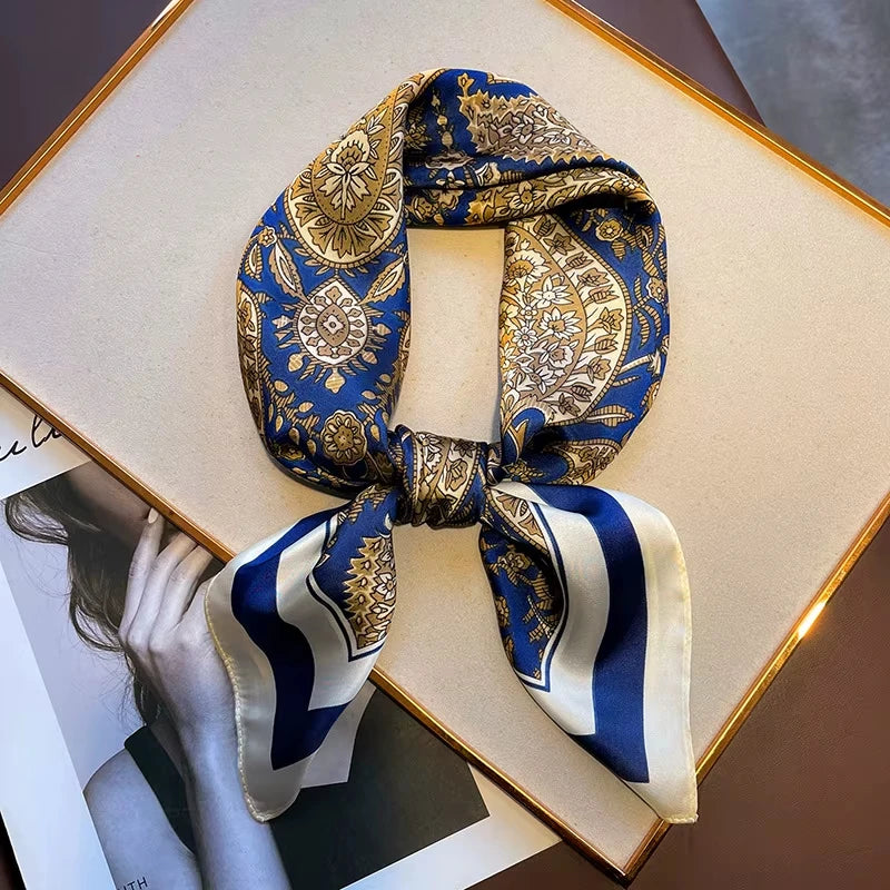 A blue and gold paisley silk hair scarf tied in a bow, displayed on a framed photo.