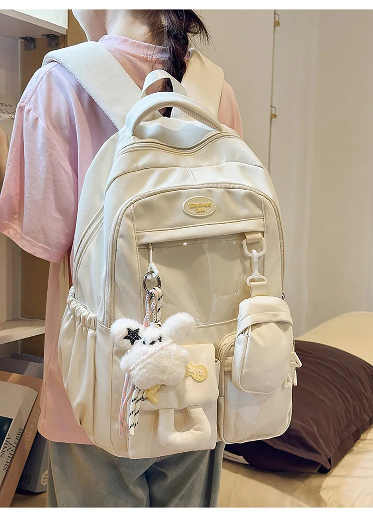 A cream-colored Kawaii Harajuku backpack with a laptop compartment is worn by a person.