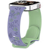 Reloj inteligente plateado con correa de silicona floral morada y una banda verde claro.