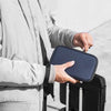A person holds a dark blue waterproof RFID blocking passport holder in their hand against a light gray jacket.