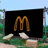 A black banner featuring a glowing yellow McDonald's 'M' logo displayed outdoors.