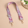 A pink and white bohemian printed crossbody strap is displayed against a neutral background.