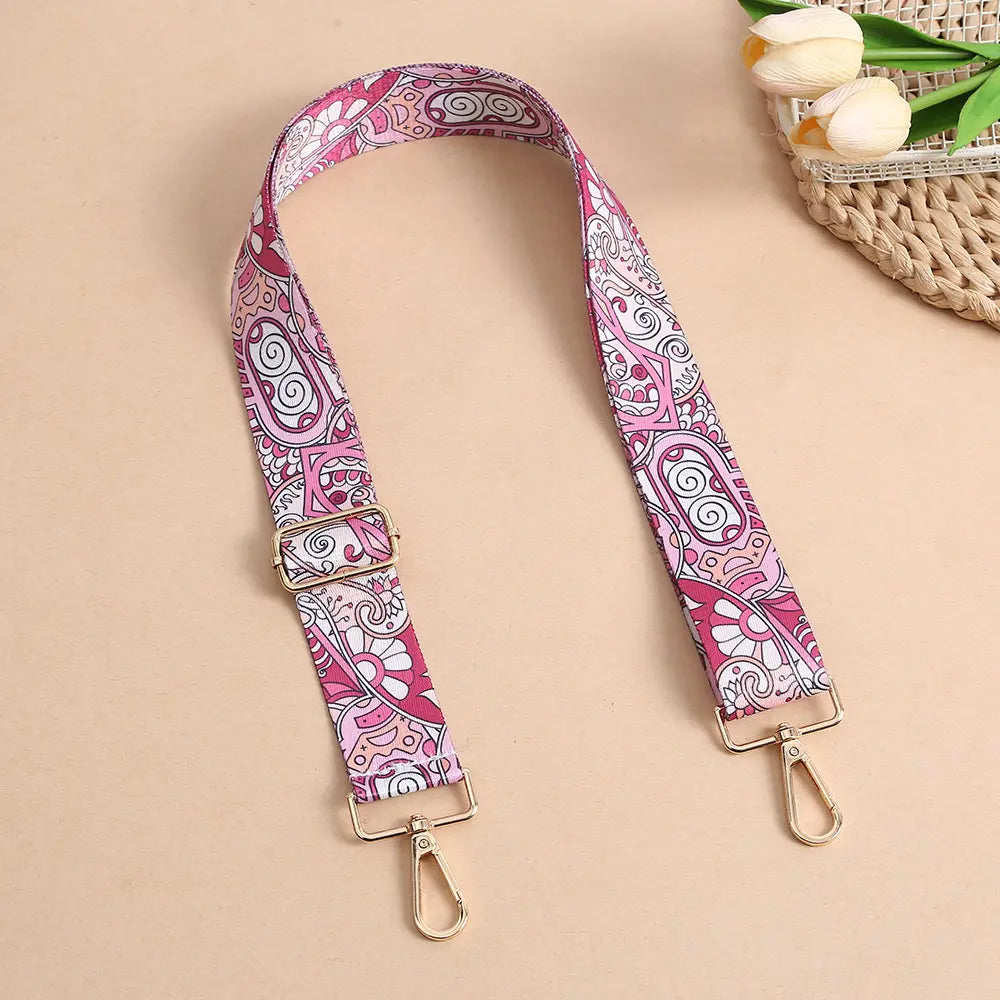 A pink and white bohemian printed crossbody strap is displayed against a neutral background.