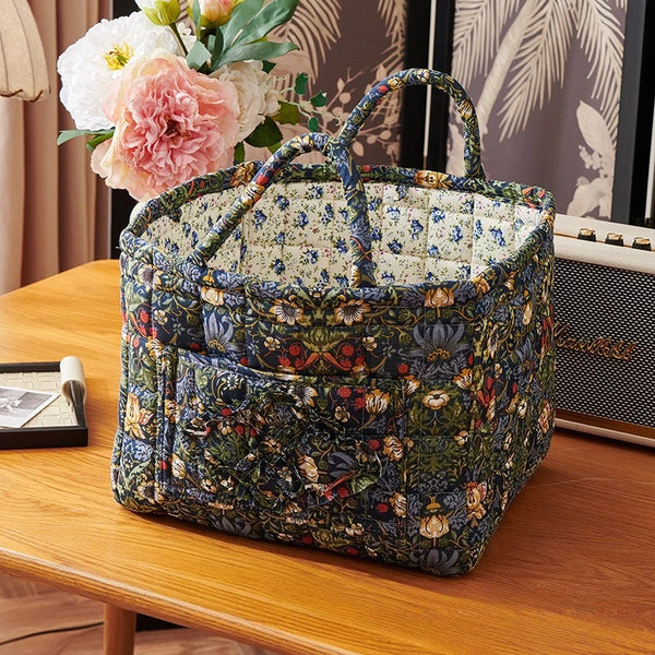 A woven floral fabric storage bin with handles sits on a wooden table.