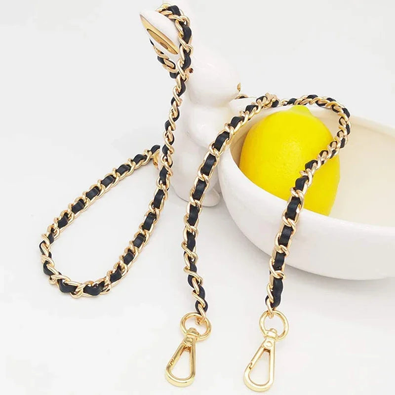 Gold and black braided metal shoulder strap for a crossbody bag displayed next to a yellow lemon