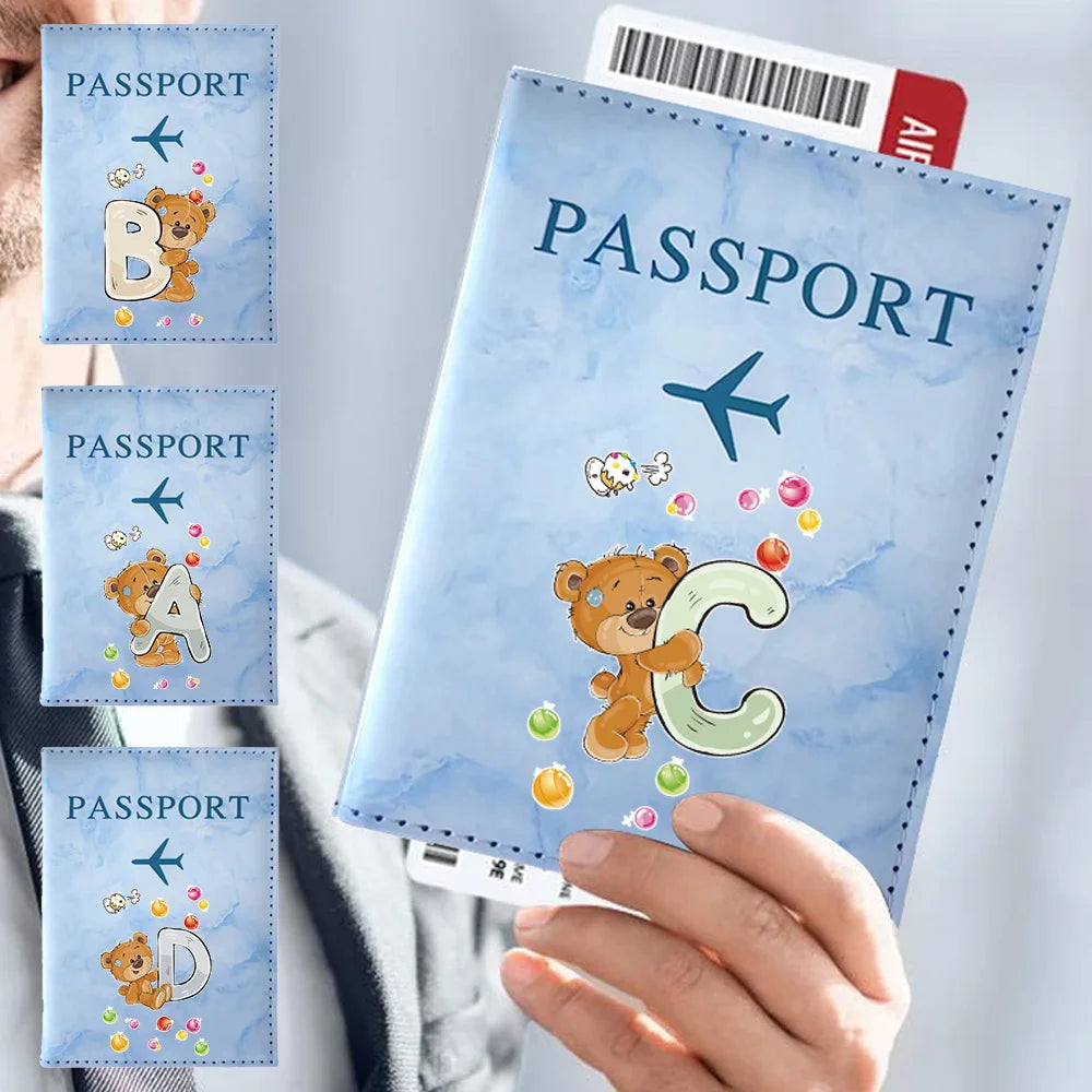 A hand holds a blue passport card holder featuring a vintage letter print design.
