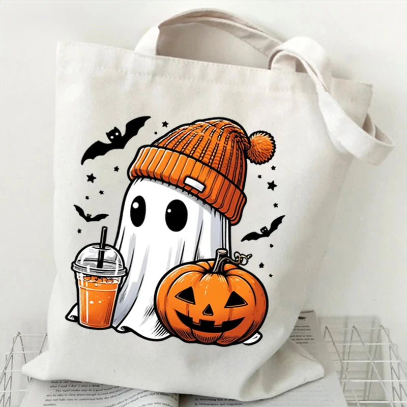 A white canvas tote bag featuring a black ghost and an orange pumpkin print with bats.