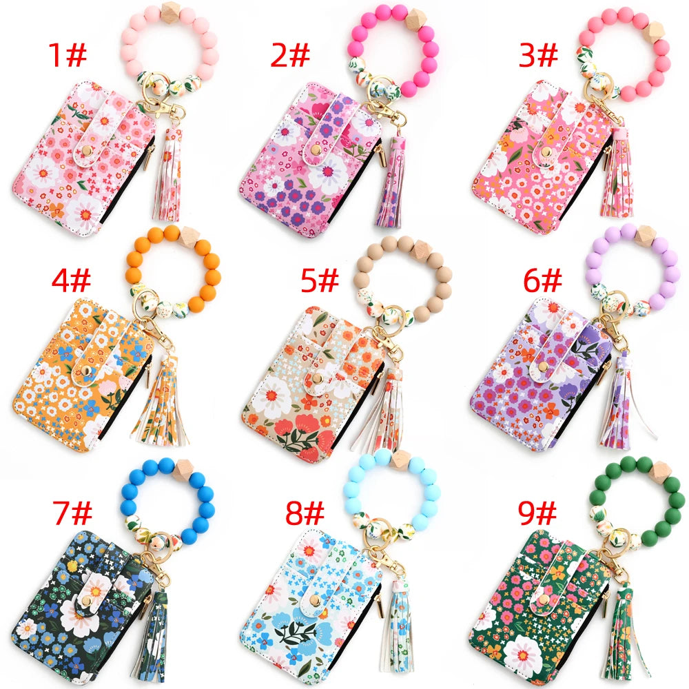 Nine colorful silicone bead PU leather key chain wallets featuring floral patterns and charms.
