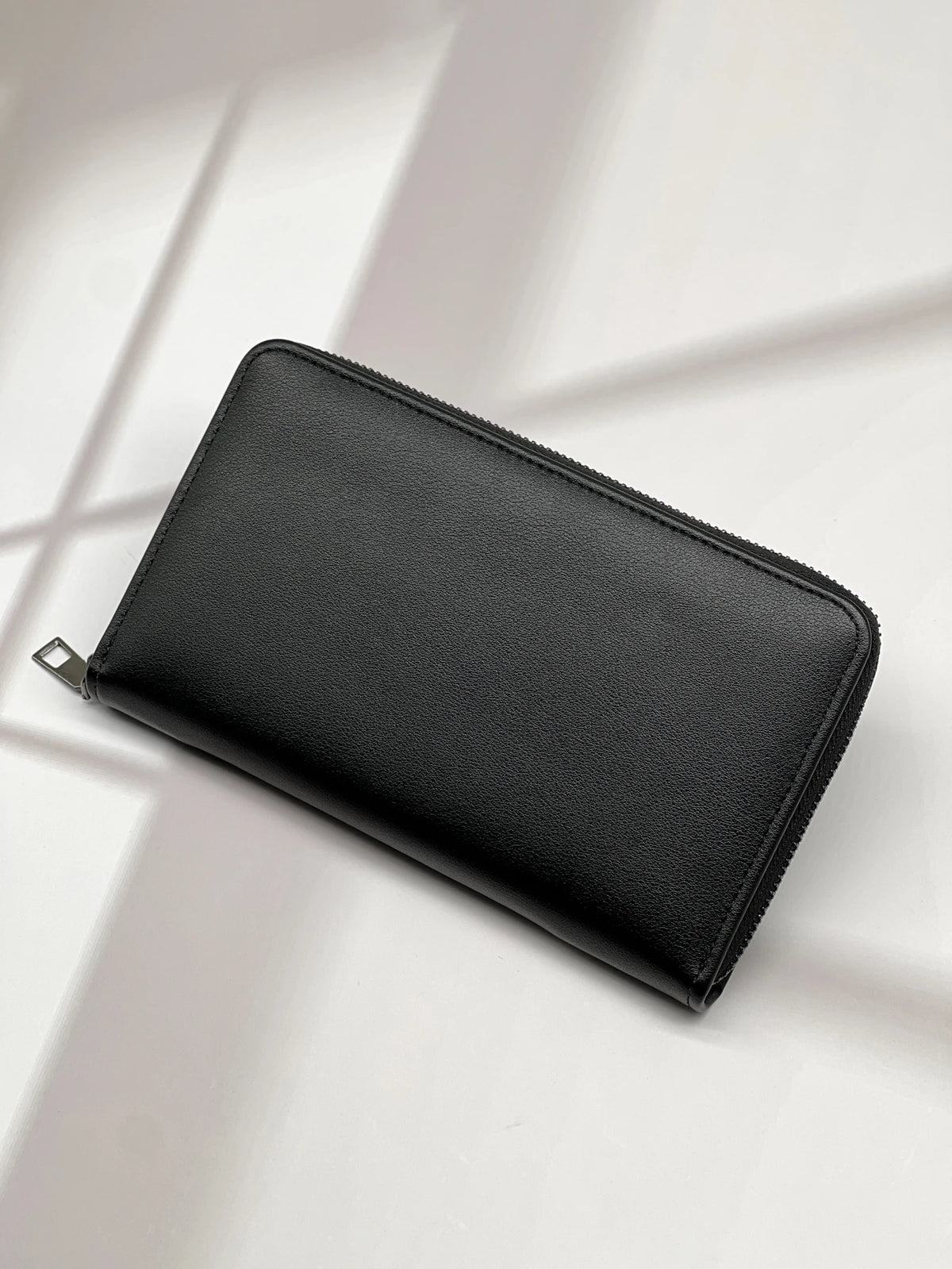 A black multi-card men's commuter wallet lying on a light surface with shadows.