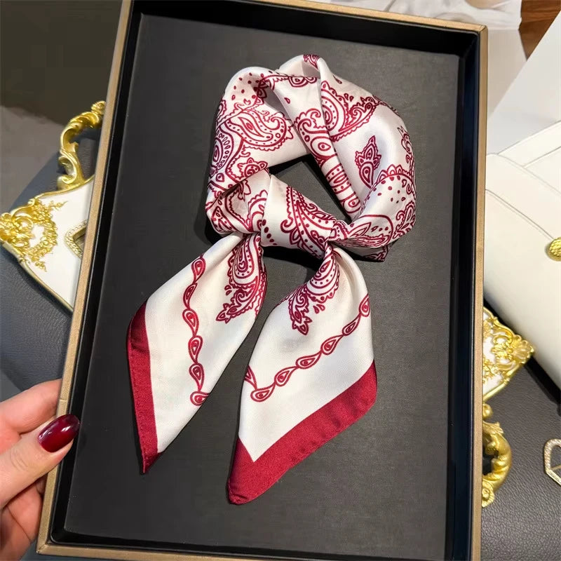 Elegant paisley silk hair scarf tied in a knot with red trim displayed in a black box.